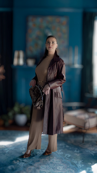 A model in a vintage burgundy belle belted trench coat in a size large